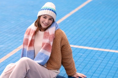 Beautiful woman in warm scarf and hat outdoors, space for text