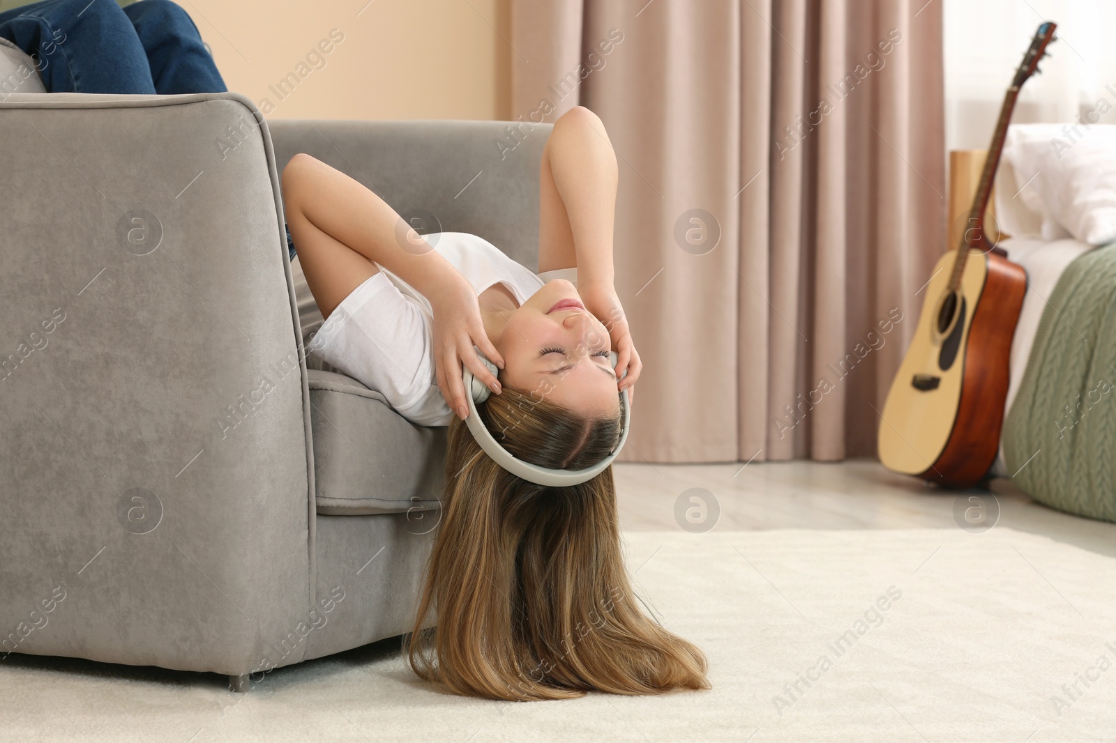 Photo of Teenage girl listening to music with headphones at home. Space for text