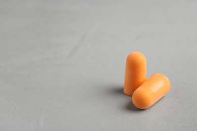 Pair of orange ear plugs on grey background. Space for text