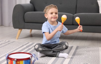 Little boy playing toy maracas at home