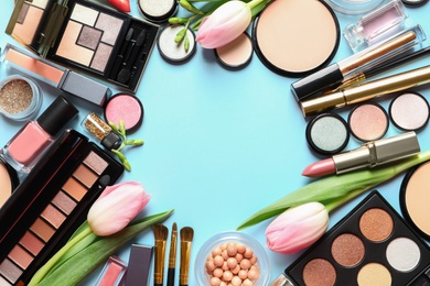 Different makeup products and flowers on color background, flat lay with space for text