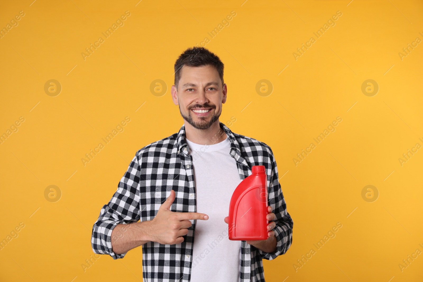 Photo of Man pointing at red container of motor oil on orange background