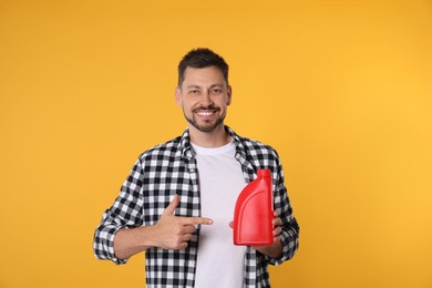 Photo of Man pointing at red container of motor oil on orange background