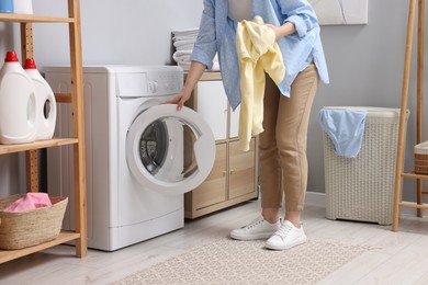 Photo of Woman with sweatshirt near washing machine in laundry room, closeup