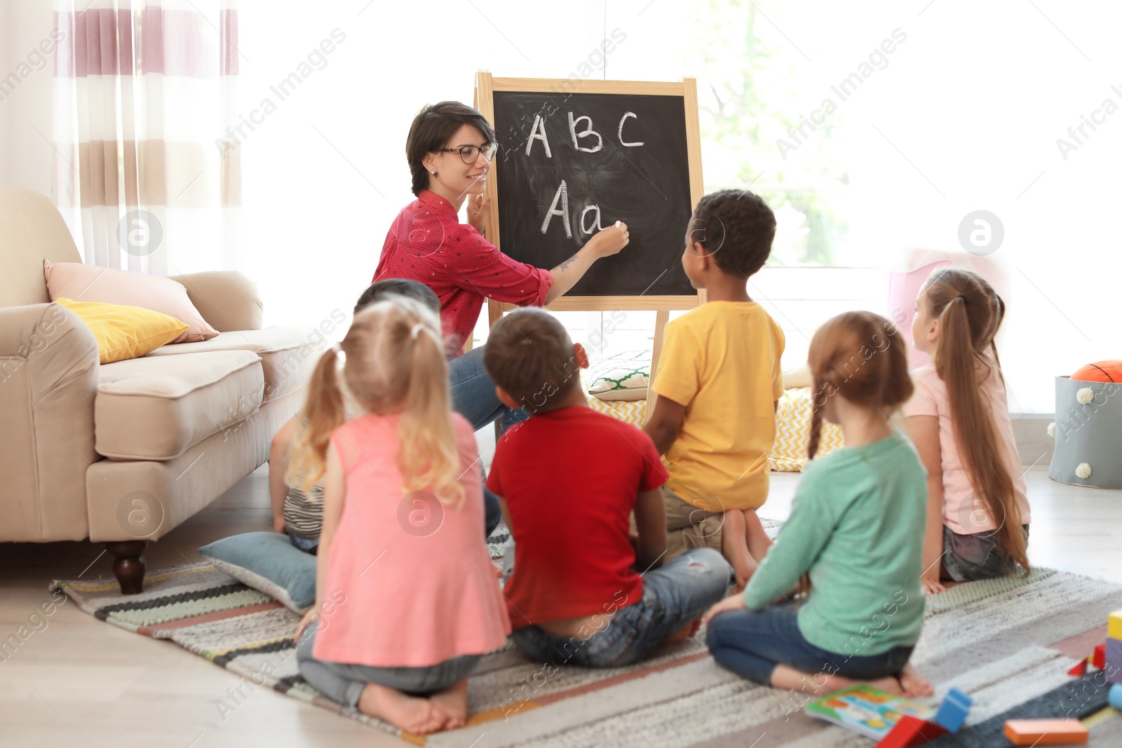 Photo of Young woman teaching little children indoors. Learning by playing