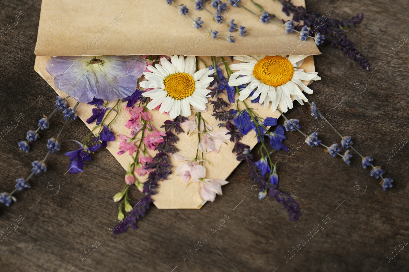 Photo of Composition with beautiful dried flowers in envelope on wooden background
