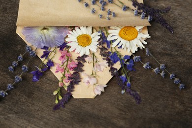 Composition with beautiful dried flowers in envelope on wooden background