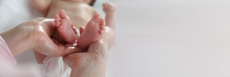 Mother massaging her cute baby with oil, closeup. Banner design with space for text