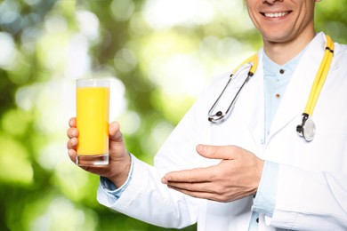 Nutritionist with glass of juice on blurred green background, closeup