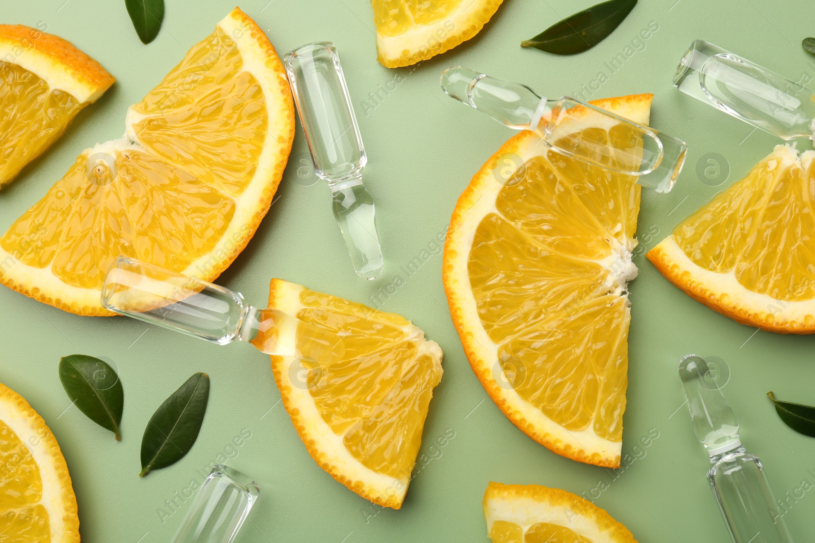 Photo of Skincare ampoules with vitamin C, slices of orange and leaves on light green background, flat lay