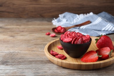 Photo of Freeze dried and fresh strawberries on wooden table. Space for text