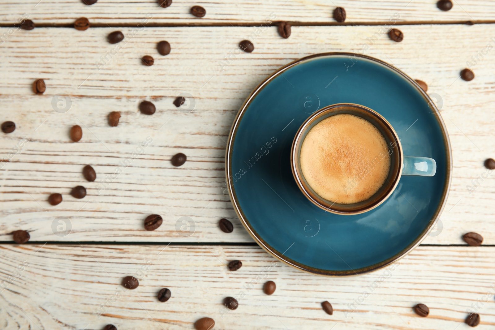 Photo of Cup of hot aromatic espresso and roasted beans on white wooden table, flat lay