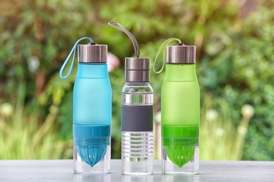 Photo of Sports water bottles on table against blurred background