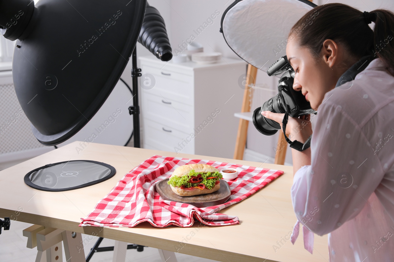 Photo of Young woman with professional camera taking photo of sandwich in studio. Food photography