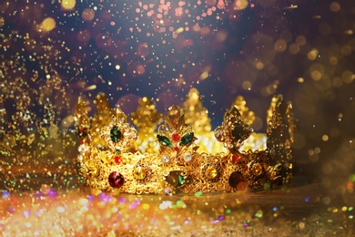 Image of Fantasy world. Beautiful golden crown lit by magic light on table, bokeh effect