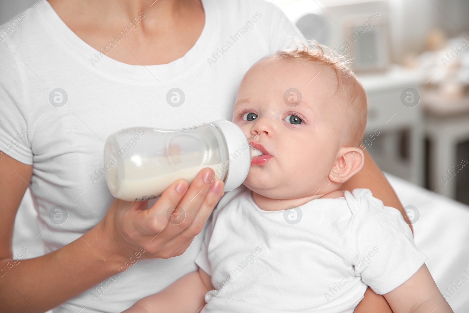 Photo of Lovely mother holding and feeding her baby from bottle, closeup