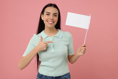Happy young woman pointing at blank white flag on pink background. Mockup for design