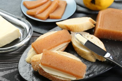 Tasty sandwiches with quince paste served on black wooden table, closeup