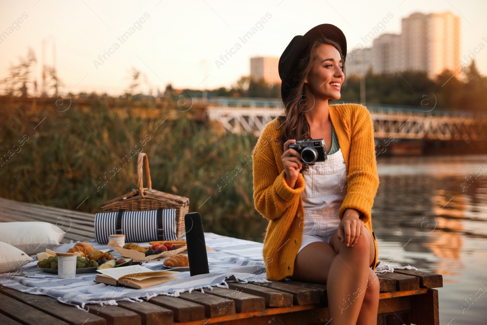 Photo of Young woman with camera on pier at picnic