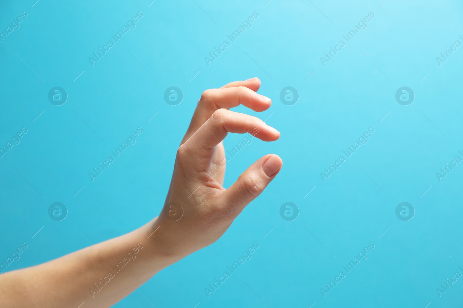 Photo of Woman holding something in hand on light blue background, closeup