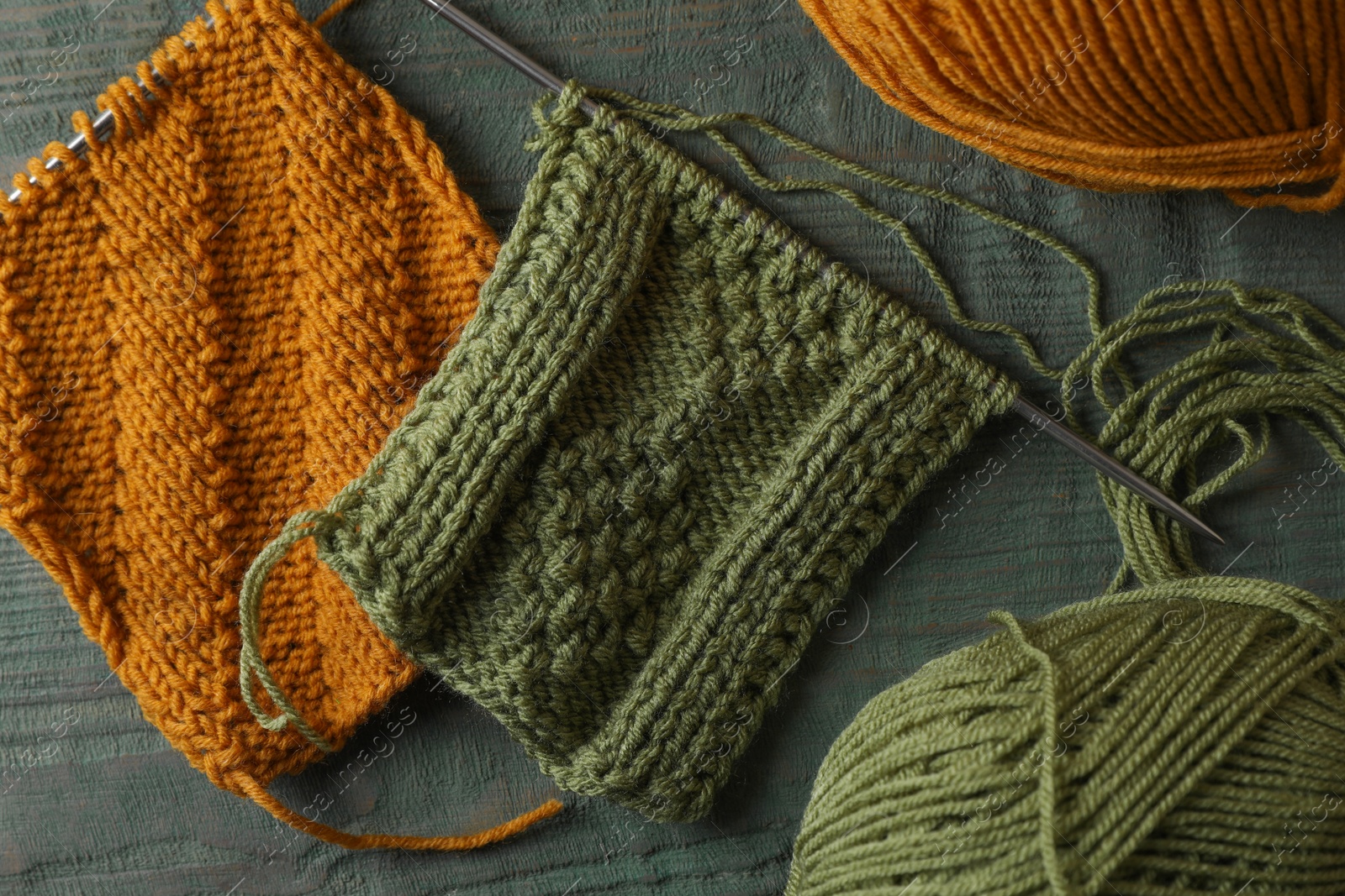 Photo of Soft yarns, knitting and metal needles on light blue wooden table, flat lay