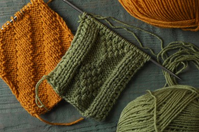 Photo of Soft yarns, knitting and metal needles on light blue wooden table, flat lay