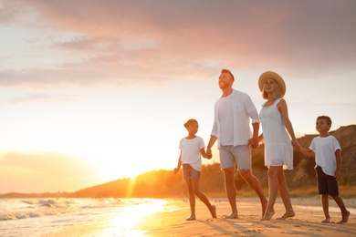 Photo of Happy family on sandy beach near sea at sunset