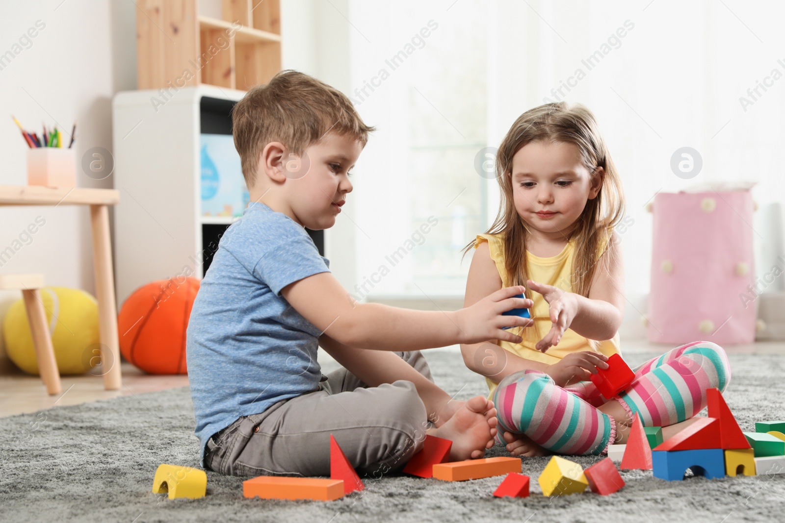 Photo of Little children playing with colorful blocks indoors