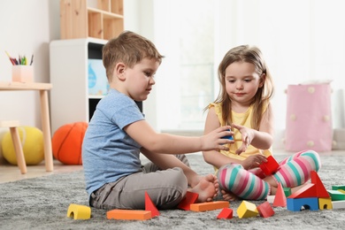 Little children playing with colorful blocks indoors