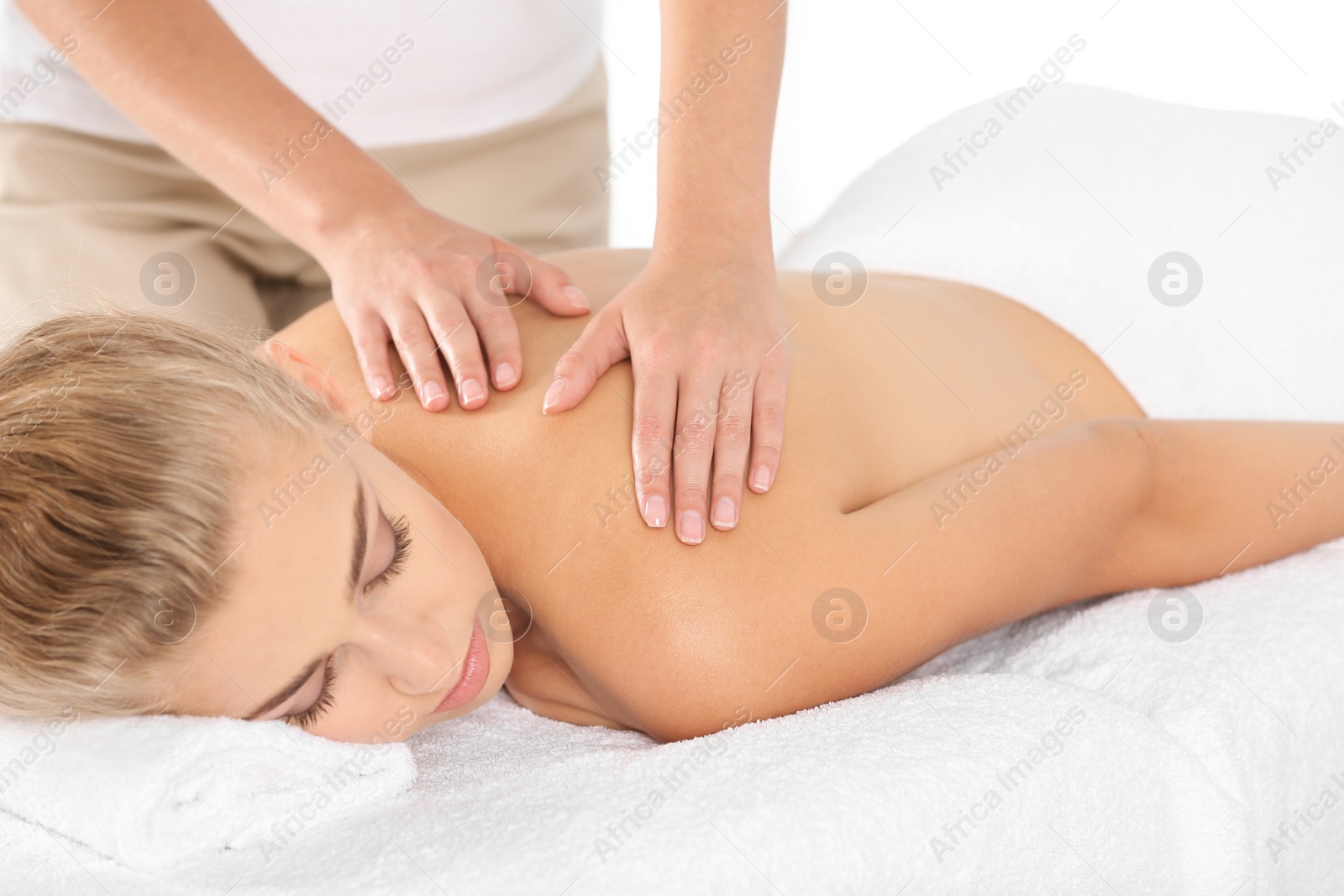 Photo of Relaxed woman receiving shoulders massage in wellness center