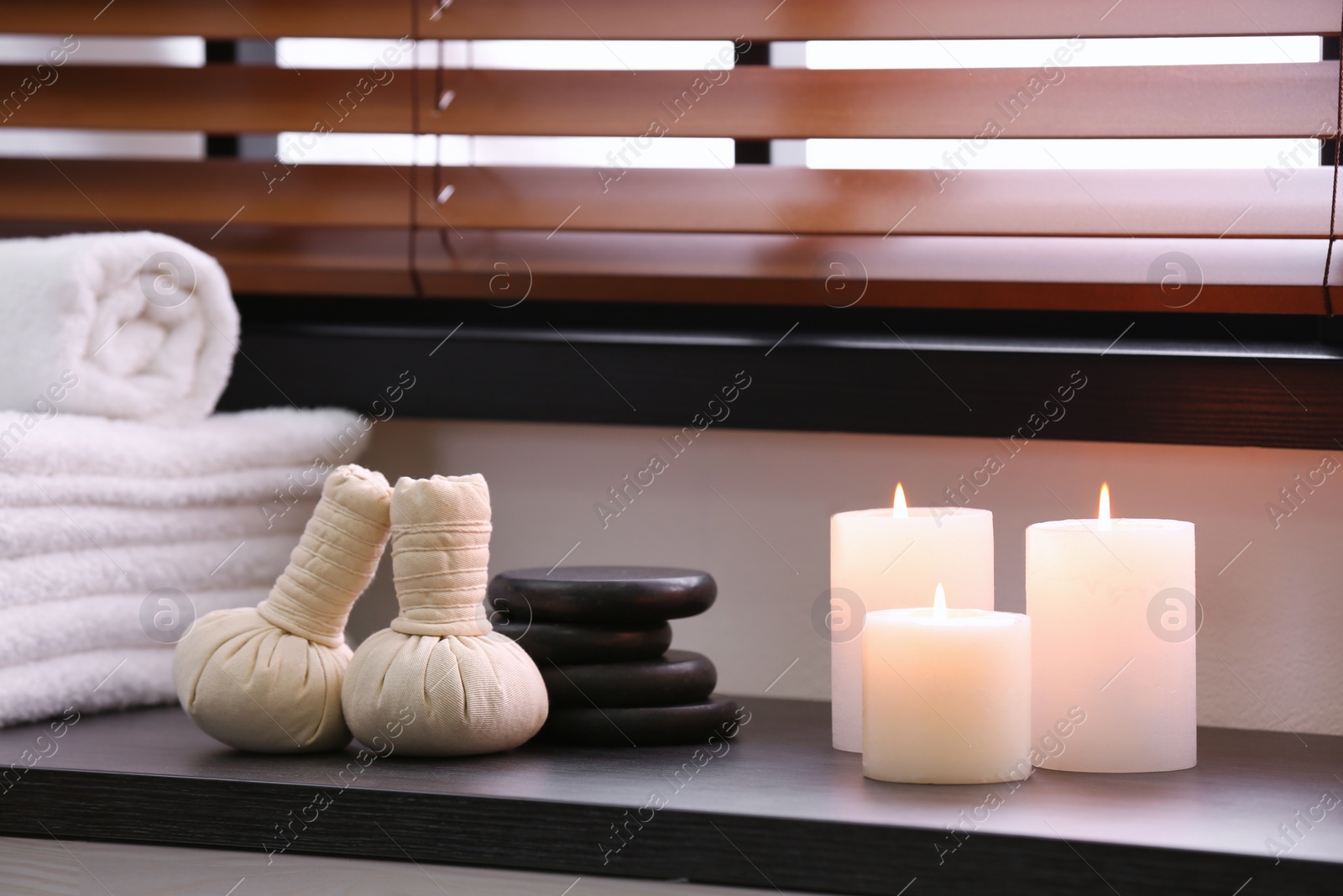 Photo of Composition with herbal bags, candles and stones near window in spa salon