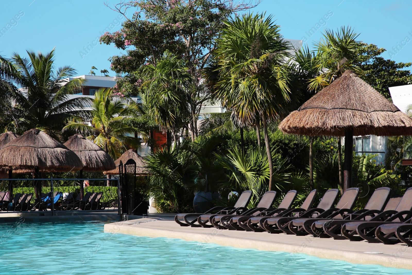 Photo of Outdoor swimming pool with sunbeds at resort on sunny day