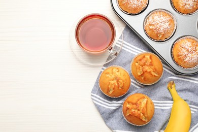 Flat lay composition with tasty banana muffins and tea on white wooden table. Space for text