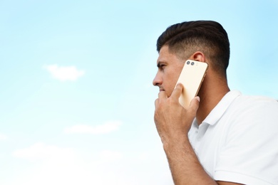 Photo of Man talking on modern mobile phone outdoors