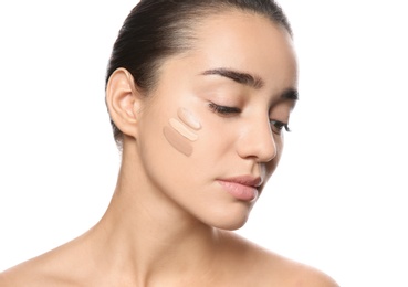 Young woman with different shades of skin foundation on her face against white background