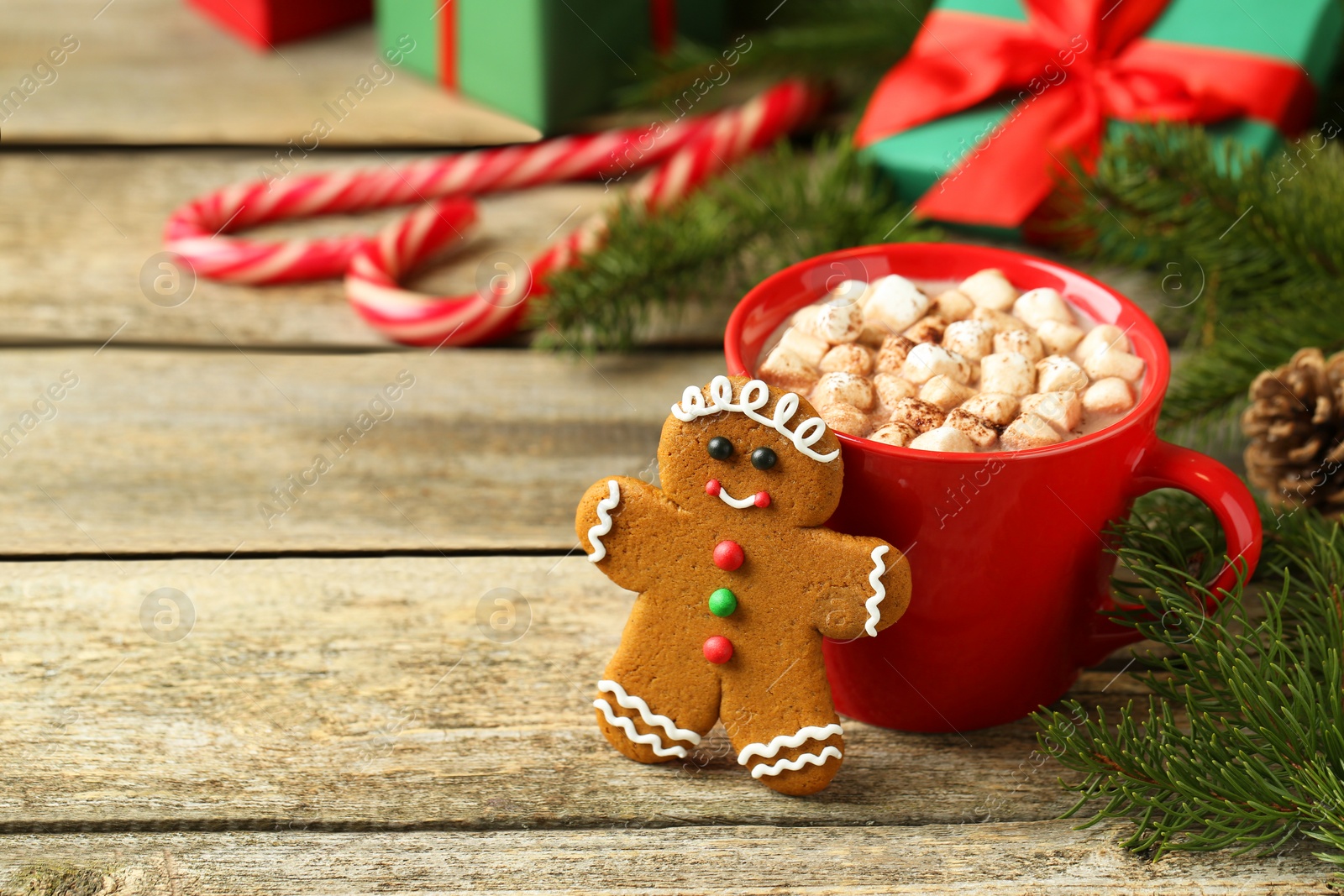 Photo of Tasty gingerbread man cookie and cocoa with marshmallows on wooden table. Space for text