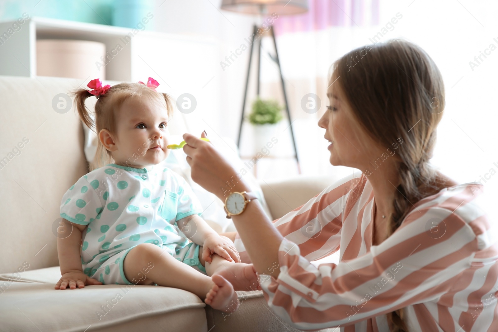 Photo of Caring mother feeding her cute little baby with healthy food at home