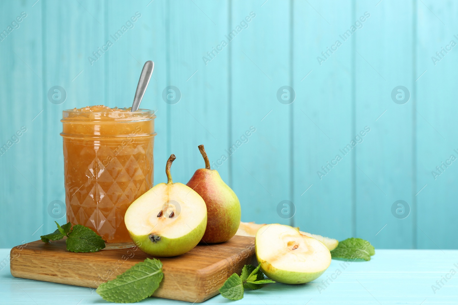 Photo of Tasty homemade pear jam and fresh fruits on light blue wooden table. Space for text