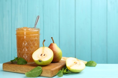 Photo of Tasty homemade pear jam and fresh fruits on light blue wooden table. Space for text