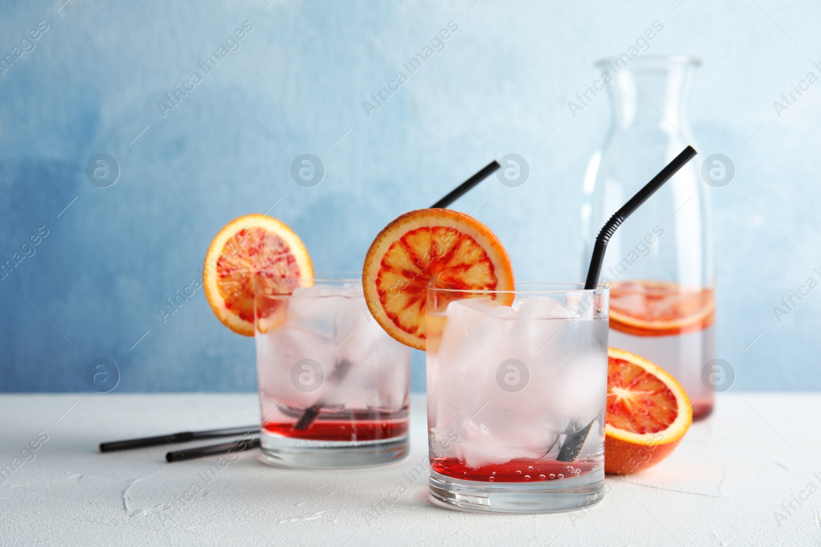 Photo of Composition with orange drink and ice cubes in glasses on table. Space for text