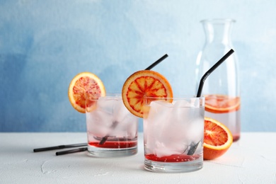 Composition with orange drink and ice cubes in glasses on table. Space for text