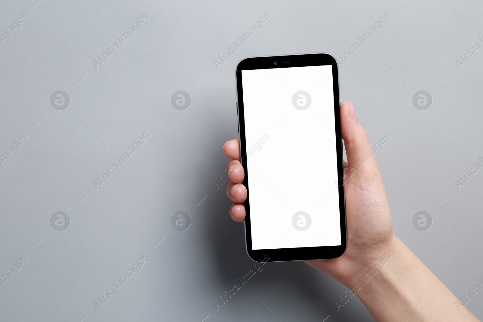 Photo of Woman holding smartphone with blank screen on grey background, closeup. Mockup for design