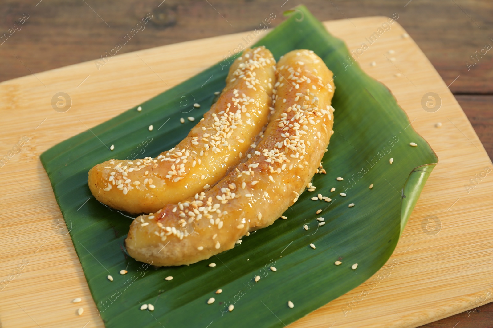 Photo of Board with delicious fried bananas on wooden table, closeup