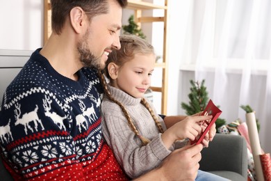 Happy man receiving greeting card from his daughter at home