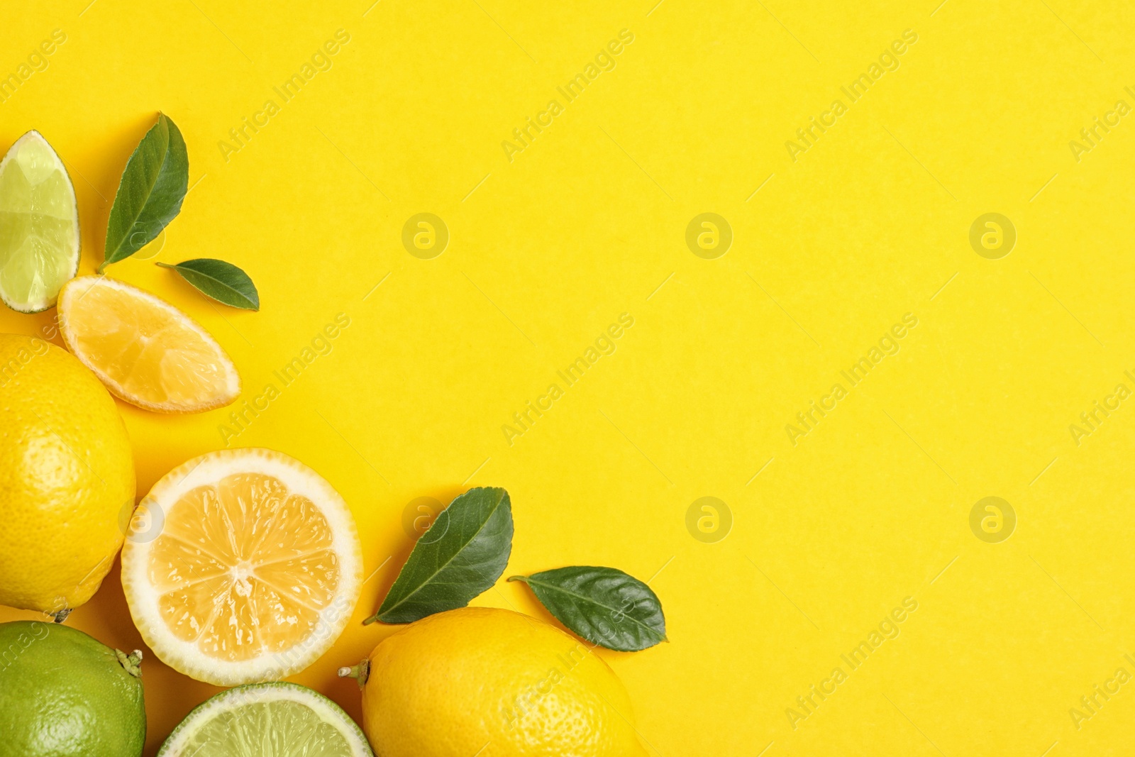 Photo of Fresh ripe lemons, limes and green leaves on yellow background, flat lay. Space for text