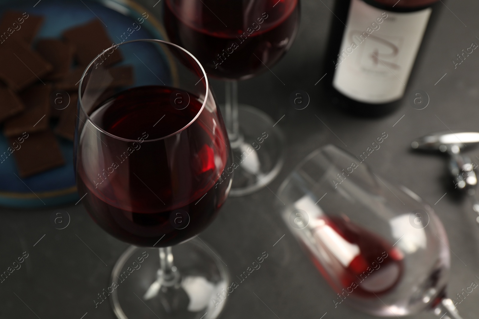 Photo of Tasty red wine and chocolate on black table, closeup. Space for text