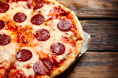 Photo of Hot delicious pepperoni pizza on wooden table, closeup