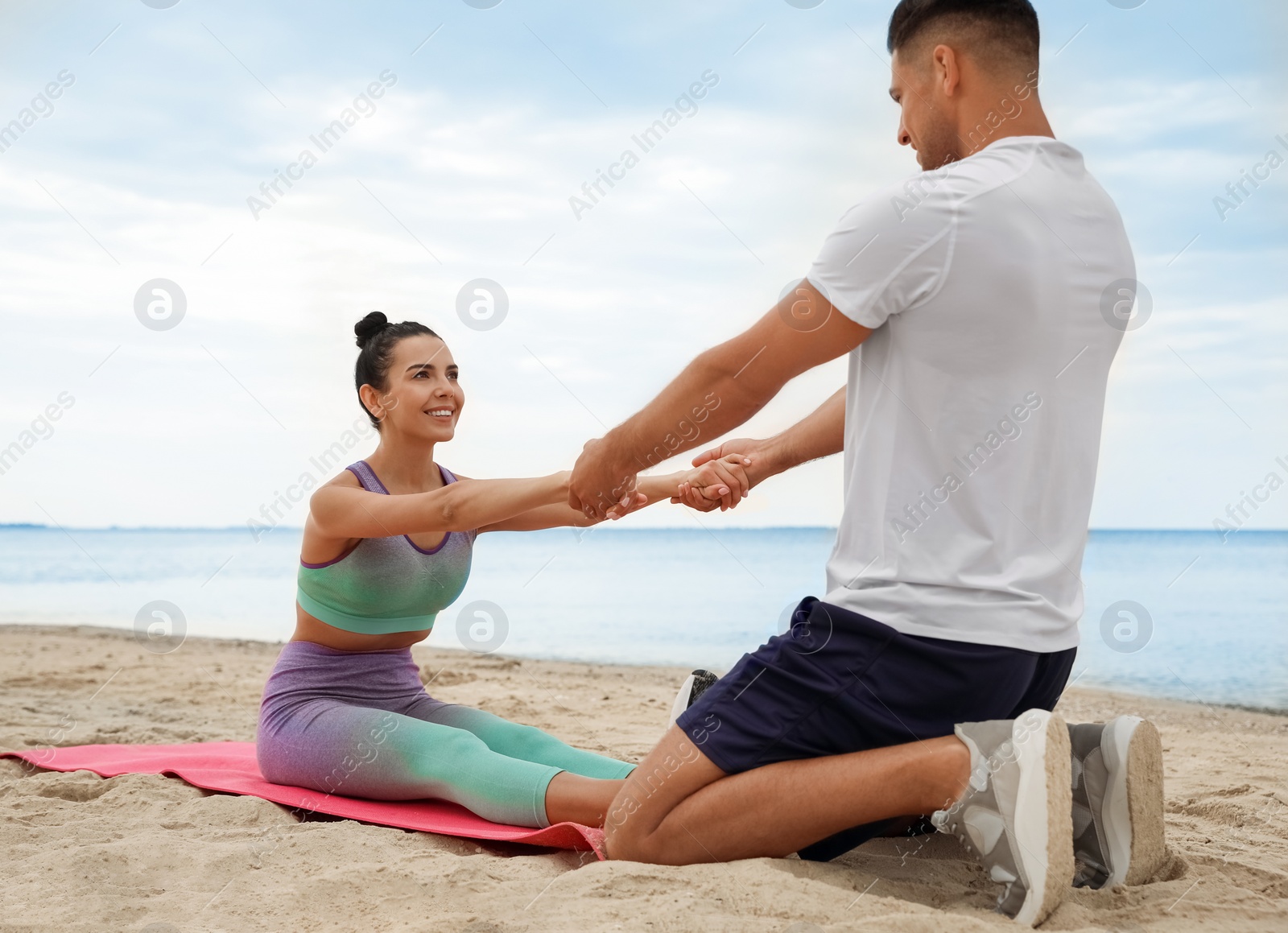 Photo of Couple doing exercise together on beach. Body training