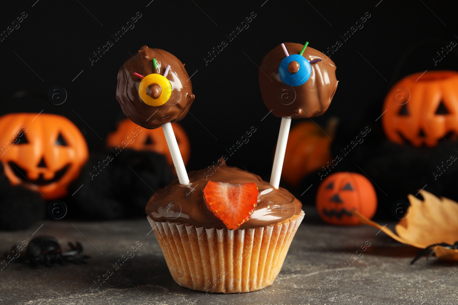 Photo of Delicious desserts decorated as monsters on grey table. Halloween treat