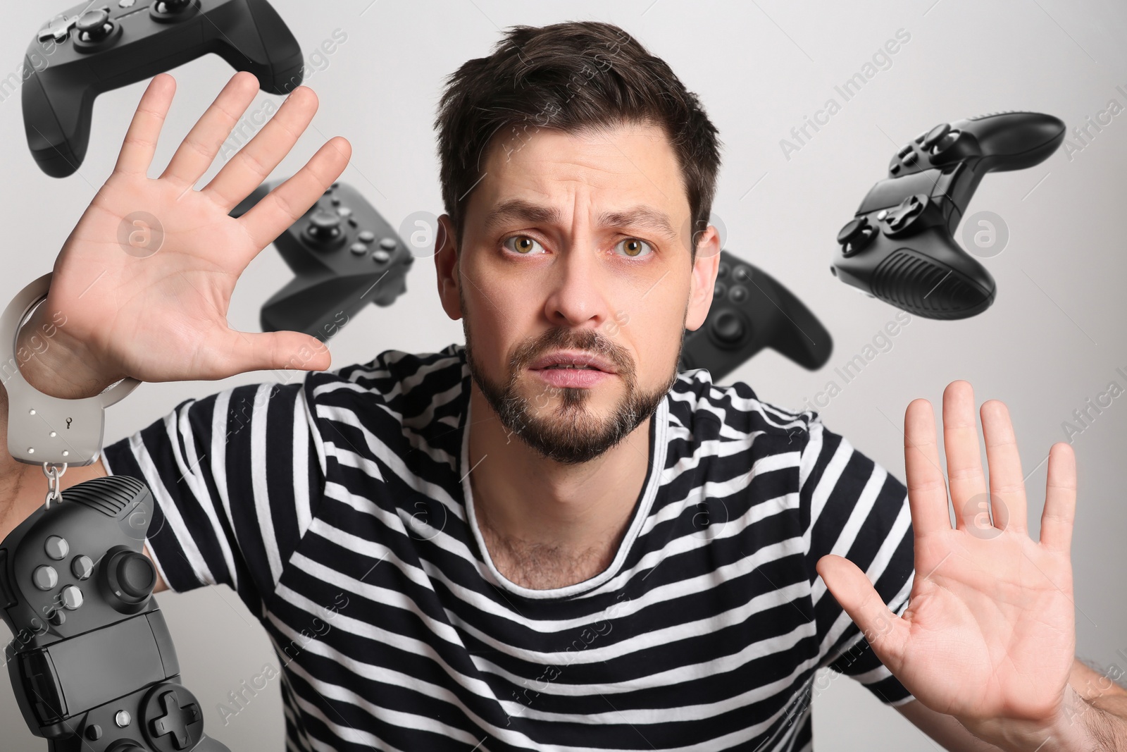 Image of Gaming disorder. Man handcuffed with gamepad stuck to transparent screen